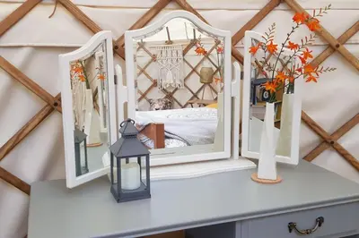 a room with mirrors on a dresser with a bed at Bronfelen Yurt in Cynghordy