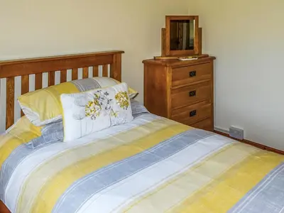 a bedroom with a bed with a wooden headboard and a dresser at Glan Wye in Rhayader