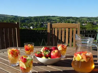 a wooden table with a bowl of fruit and glasses of juice at Glan Wye in Rhayader