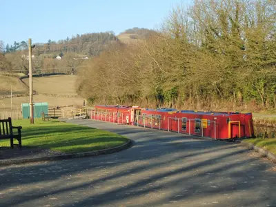 a small train traveling down a road next to a street at Llofft Stabal in Llanerfyl