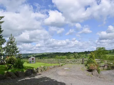 a field with a fence and a barn in the distance at Y Dderwen At Brynglas Farm in Llanfair Caereinion