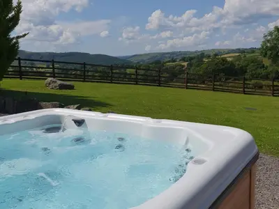 a jacuzzi tub with a view of a field at Y Dderwen At Brynglas Farm in Llanfair Caereinion