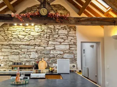 a kitchen with a stone wall with a clock on the wall at Y Dderwen At Brynglas Farm in Llanfair Caereinion