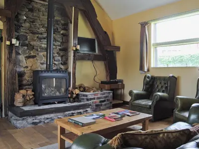 a living room with a stone fireplace at Hirros Hall Longhouse in Llanerfyl