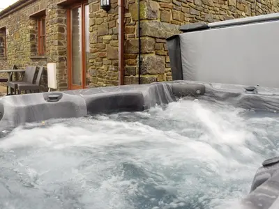 a jacuzzi tub with water in front of a building at Tan-Y-Derwwen in Mydroilin