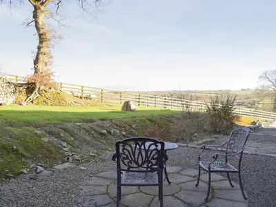 two chairs and a table in front of a fence at Tan-Y-Derwwen in Mydroilin
