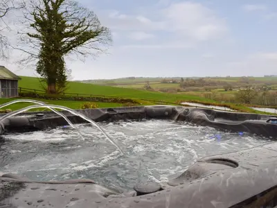 a hot tub with a water fountain in a yard at The Farmhouse in Mydroilin