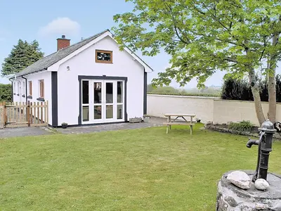 a white house with a picnic table in a yard at Panteg Cottage in Cross Inn