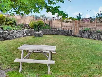 a picnic table in a yard with a fence at Panteg Cottage in Cross Inn