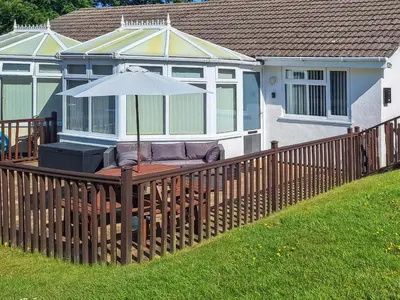 a wooden deck with an umbrella on a house at Bwthyn Gwyn in Ciliau-Aeron