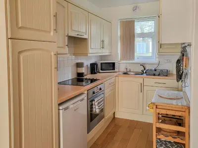 a kitchen with white cabinets and a stove top oven at Bwthyn Gwyn in Ciliau-Aeron