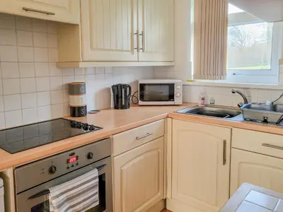 a kitchen with white cabinets and a sink and a microwave at Bwthyn Gwyn in Ciliau-Aeron