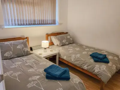 a bedroom with two beds and a table and a window at Bwthyn Gwyn in Ciliau-Aeron
