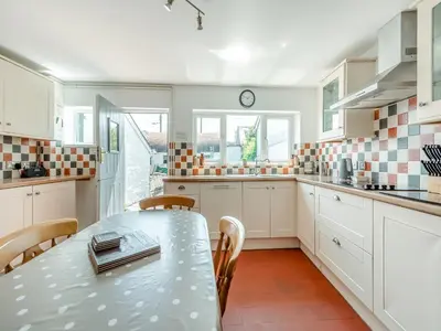 a white kitchen with a table and chairs in it at Glendower in Aberaeron