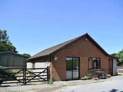 a brick house with a fence and a table at Greenmeadow Bungalow in Llanon