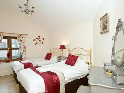 two beds in a room with a mirror at Magnolia Cottage in Aberaeron