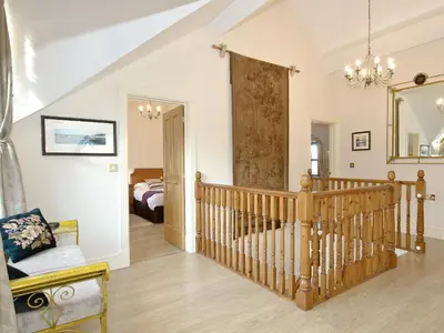 a living room with a staircase and a bedroom at Magnolia Cottage in Aberaeron