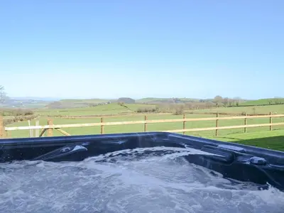 a bath tub filled with water in front of a field at Bryncrwn Cottage in Rhyd-y-felin