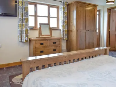 a bedroom with a bed and a dresser and a mirror at Bryncrwn Cottage in Rhyd-y-felin