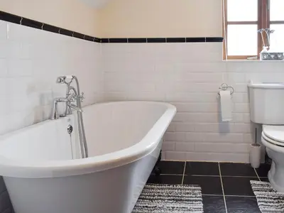 a white bathroom with a tub and a toilet at Bryncrwn Cottage in Rhyd-y-felin