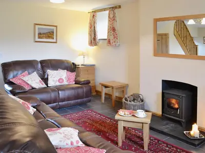a living room with a leather couch and a fireplace at Llechwedd Mawr in Scyborycoed