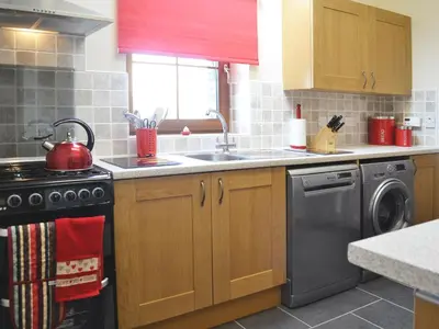 a kitchen with a stove and a washing machine at Llechwedd Mawr in Scyborycoed