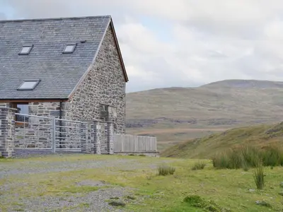 an old stone house on a hill with mountains in the background at Llechwedd Mawr in Scyborycoed