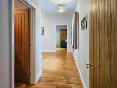 a hallway with a wooden floor and a door at Beudy-Oh2 in Dihewid
