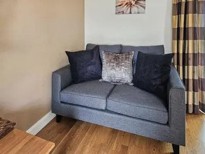a gray couch with pillows in a living room at Beudy-Oh2 in Dihewid