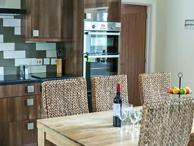 a kitchen with a table with a bottle of wine at Beudy-Oh2 in Dihewid