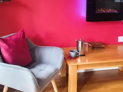 a living room with a chair and a wooden table at Cartws-Oh3 in Dihewid