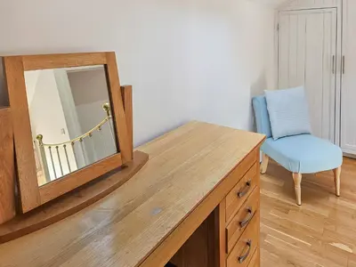 a mirror on top of a wooden dresser with a chair at Stabl-Oh4 in Dihewid
