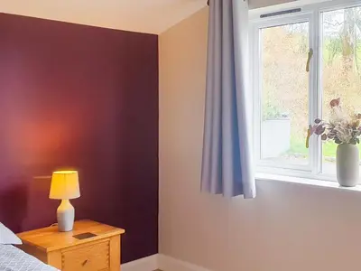 a bedroom with a window and a table with a lamp at Beudy Bach-Oh5 in Dihewid