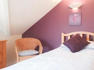 a bedroom with a bed and a chair at Beudy Bach-Oh5 in Dihewid