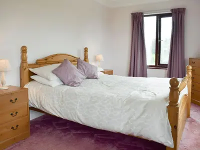 a bedroom with a large bed with purple curtains at Bryneirin in Tal-gareg
