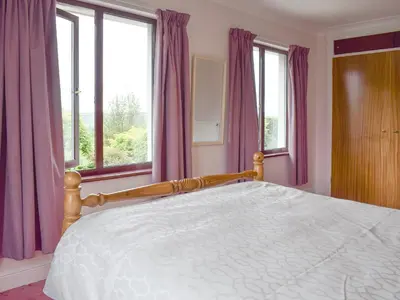 a bedroom with a large bed with purple curtains at Bryneirin in Tal-gareg