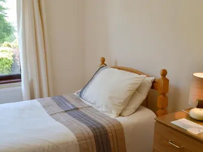 a bedroom with a bed with a pillow and a window at Bryneirin in Tal-gareg
