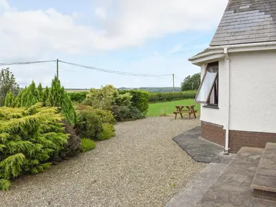 a garden with a picnic table next to a building at Bryneirin in Tal-gareg