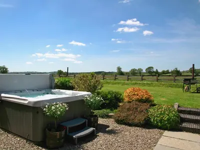 a hot tub in a garden with a field at Bwthyn Onnen-Oa5 in Ystrad Meurig