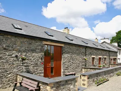 a stone building with a bench in front of it at Bwthyn Derwen - Oa7 in Ystrad Meurig