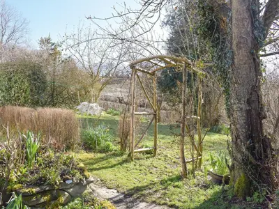 an old arbor in a garden next to a tree at Tynlon Villa in Bronant