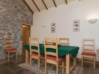 a dining room with a green table and chairs at Yr Hen Stabl in Tregaron