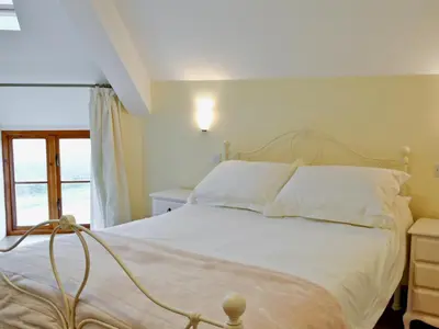 a bedroom with a bed with white sheets and a window at Felin Hedd Peaceful Mill in Tregaron
