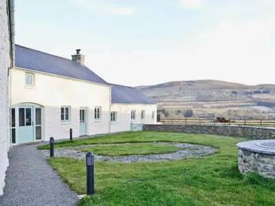 a white building with a grass yard next to a building at Felin Hedd Peaceful Mill in Tregaron