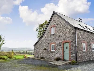 a stone barn with a green door on a field at Marlais in Llangadog