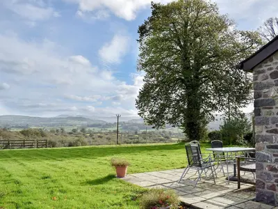 a patio with a table and chairs and a tree at Marlais in Llangadog
