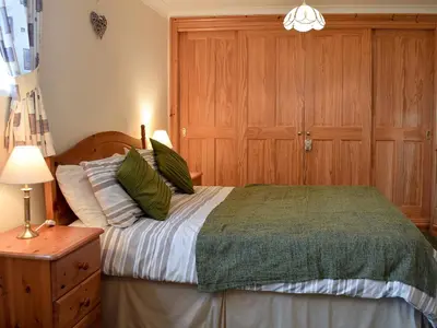 a bedroom with a bed with a green comforter at Penybryn in Llansadwrn