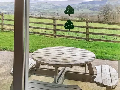 a wooden table and bench in front of a window at Penybryn in Llansadwrn