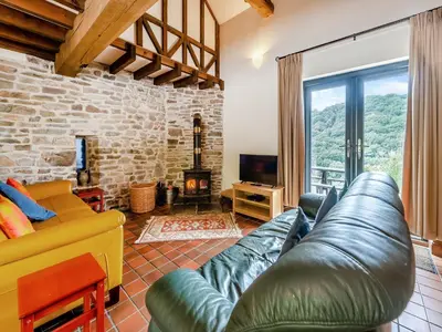 a living room with a leather couch and a fireplace at Rhyblid Fach in Myddfai