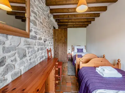 two beds in a room with a stone wall at Rhyblid Fach in Myddfai